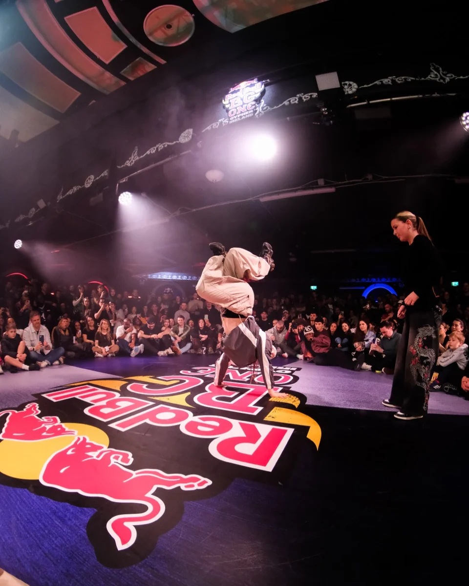 Tara performing an inverted balance at a Red Bull BC One Cypher, surrounded by spectators