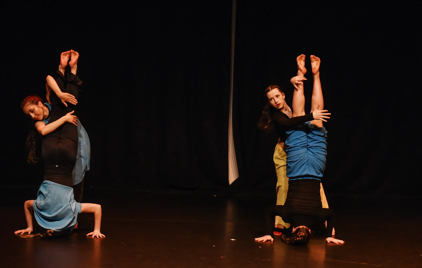 Dancers exploring inverted balances and partner work on stage