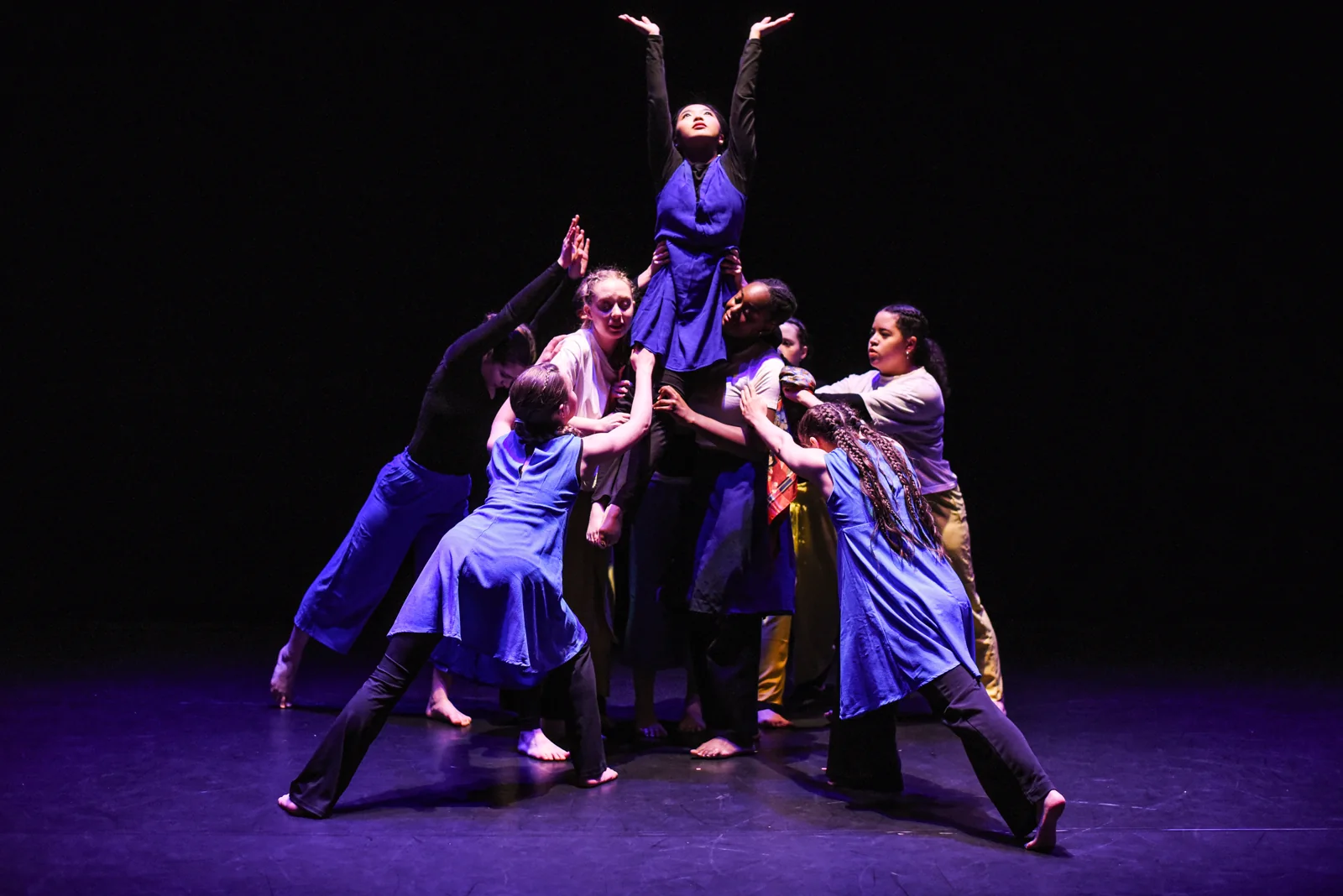An ensemble supporting a dancer reaching upward