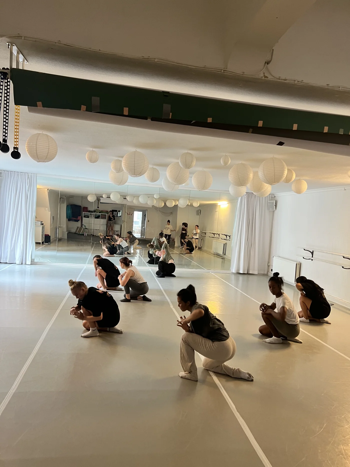 Dancers exploring floor work in a bright rehearsal studio