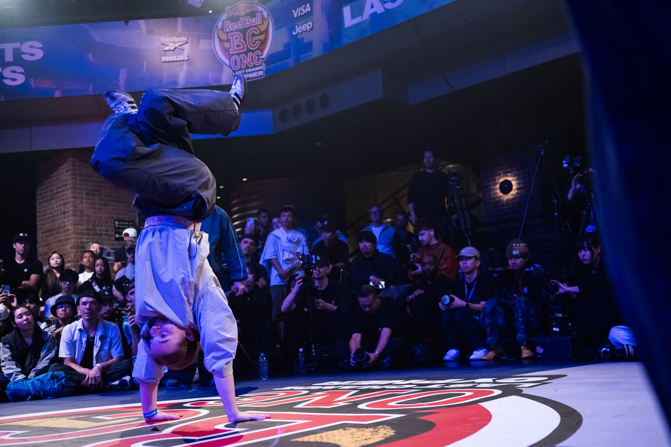 Tara holding an inverted freeze at a Red Bull BC One breaking competition, surrounded by spectators