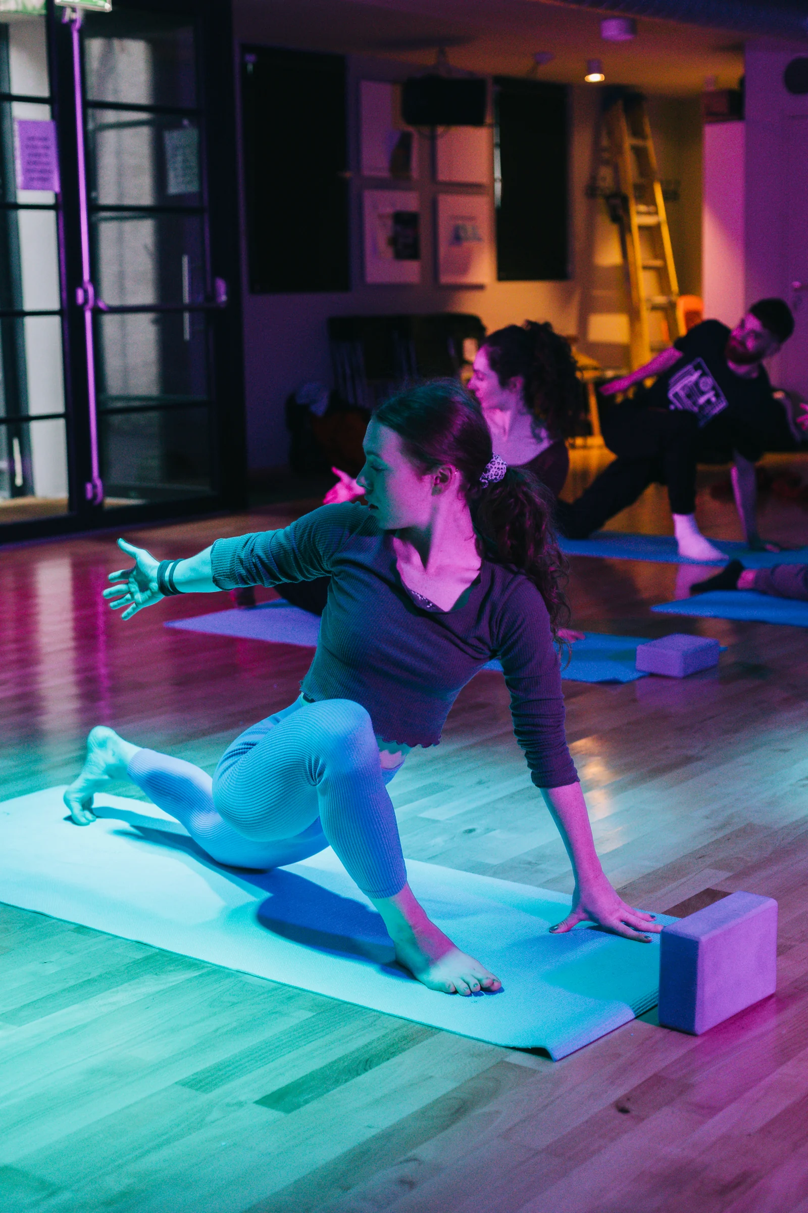 A participant exploring a seated side stretch on a Pilates mat
