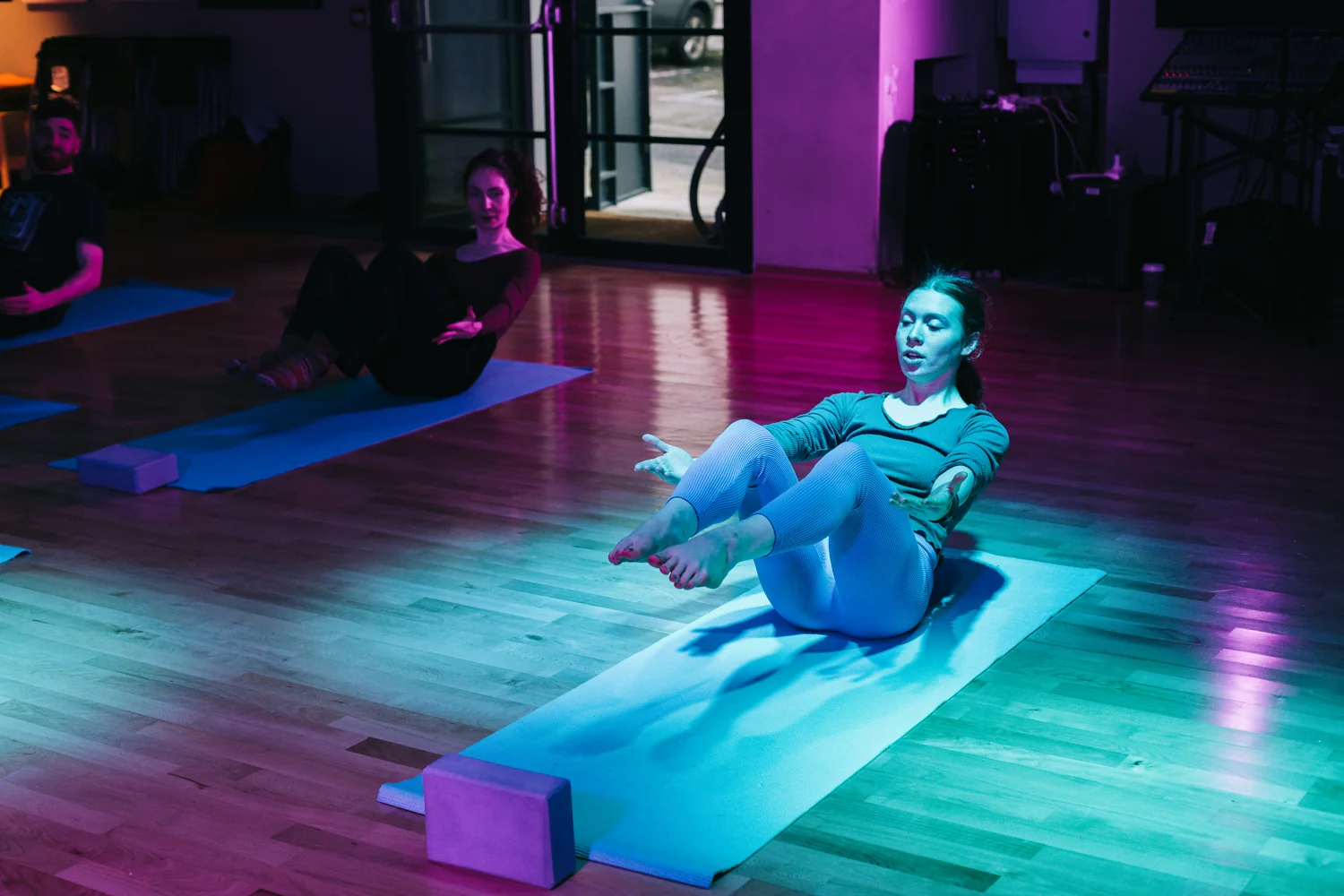Participants practising a seated Pilates balance together in the studio