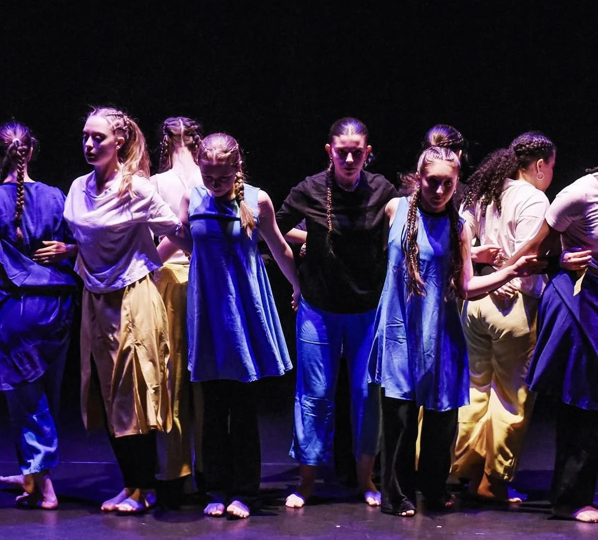 Dancers performing on stage under purple lighting